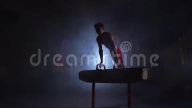 男子体操运动员在黑暗的<strong>背景</strong>上表演倒立和旋转鞍马，并缓慢地吸烟。 奥林匹克<strong>运动会</strong>